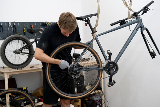 A bicycle mechanic meticulously inspects a bike in a clean workshop, ensuring everything is in optimal working condition.