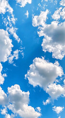 Vivid blue sky filled with large fluffy white clouds illuminated in soft natural light