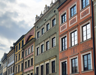 Colorful townhouses in Warsaw Old Town under cloudy sky, with ornate facades, classic windows, and