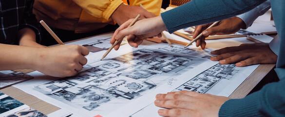 A dynamic scene showcasing a group of hands engaged in a collaborative design session, highlighting the creative process of drafting architectural plans and brainstorming ideas. SACTR