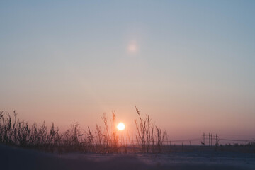 Frosty winter sunset in the field. Beautiful sunset in the snowy desert. Ice and sun..