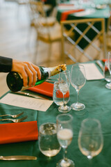Champagne is poured into glasses at a festive dining table during a celebration in an elegant venue