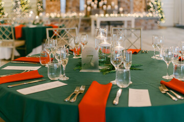 Elegant dining setup with green and red decor for a festive celebration in a beautifully decorated venue
