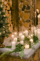 Cozy winter gathering with candles and greenery by a stone fireplace in a rustic setting