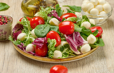 Plate of fresh salad with mixed greens, cherry tomatoes and mozzarella balls.