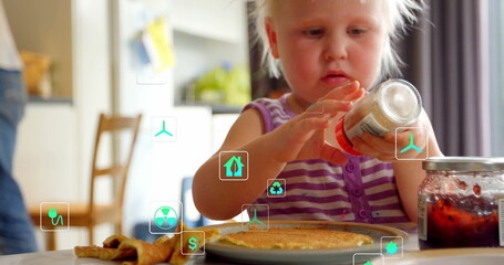 Inspecting toddler holding glass jar upside down at home kitchen table, with pancakes and jam jar