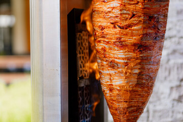 Marinated pork al pastor cooking on a vertical spit with pineapple on top, ready to be sliced for authentic Mexican tacos.
