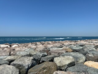 Big rocks forming the foundation and breakwater of Palm Jumeirah, artificial island in the Persian Gulf, in Dubai, UAE. View of the sea over the stones.