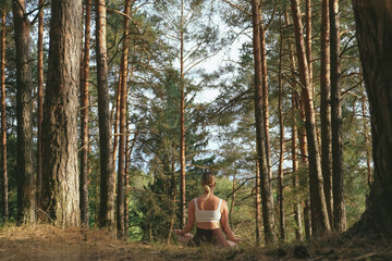 Mindful outdoor yoga in a pine forest: a woman stretches on a mat, breathes deeply, relaxes and resets. Eco-friendly wellness retreat vibe nature, calm energy, sustainable travel, digital detox.