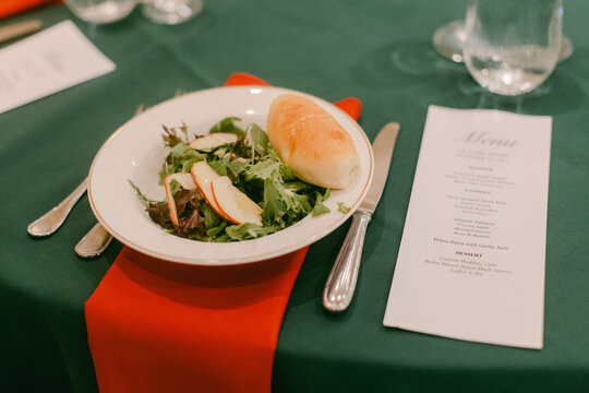 Green table setting with salad and bread in elegant dining environment during evening event