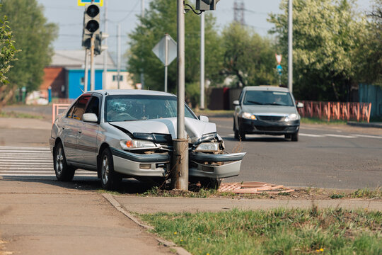 The car crashed into a pole at a crosswalk.