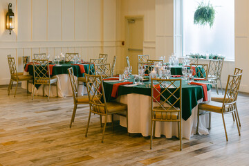 Elegant dining setup in a spacious banquet hall with green and red table settings for an event