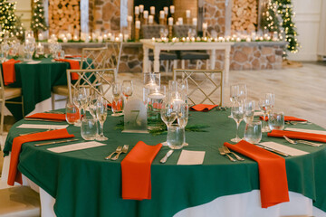 Elegant holiday dining setup with green and red decor in a cozy venue featuring a rustic fireplace
