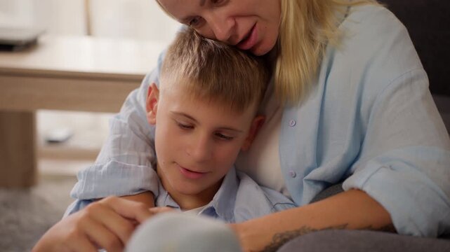 Caring mother embracing tearful teenage son, softly stroking hair and holding hands, offering emotional comfort and unconditional support during challenging moment