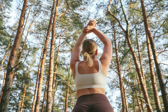 Mindful outdoor yoga in a pine forest: a woman stretches on a mat, breathes deeply, relaxes and resets. Eco-friendly wellness retreat vibe nature, calm energy, sustainable travel, digital detox.