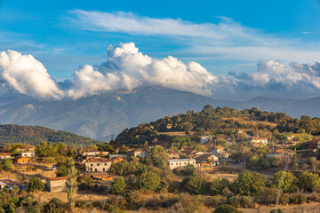 Traditional Turkish village houses on hillside with Kazdağları mountains and dramatic clouds
