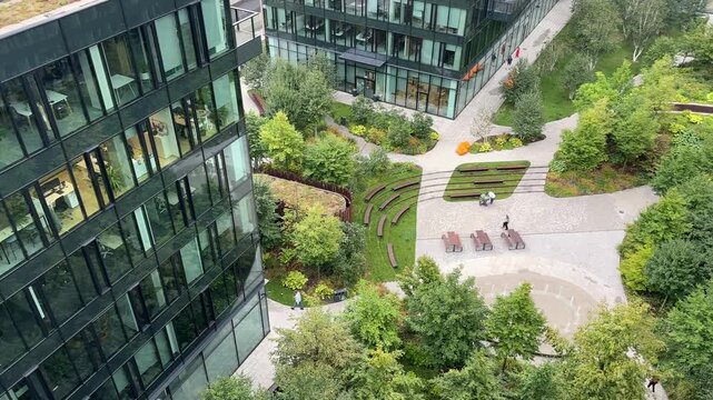 Urban garden at a modern office campus biophilic courtyard, glass facades, amphitheater benches, walkable paths showcasing green architecture, sustainability and smart-city design for community wellb