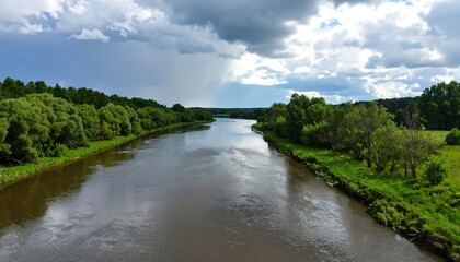 Obraz premium Serene river flows between lush green banks under a dramatic, cloudy sky