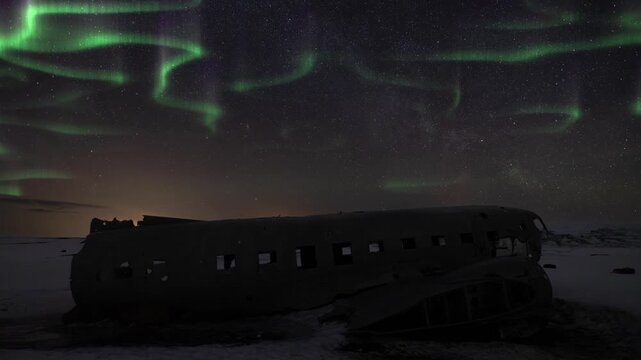 Time lapse of Aurora borealis above a crashed DC-3 Plane in Solheimasandur Iceland during winter. Tourism landmark at night with stars and sky.