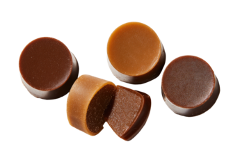 Close-up of four round, light brown and dark brown candies.  One candy is cut in half, revealing a lighter interior.  They are arranged in a loose cluster against a black background