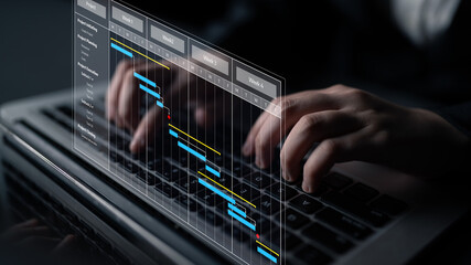 A business professional types on a laptop displaying a digital project management chart. This image represents modern workflow visualization in an office setting. Tessel