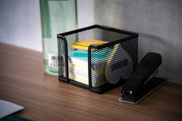 Fotografia de uma mesa de escritório com uma pequena caixa de papeis auto adesivos, post-it um...