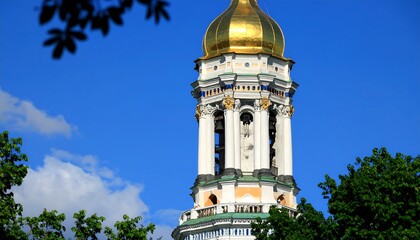 A tall, ornate bell tower rises against a vibrant blue sky, adorned with golden details and architectural embellishments.