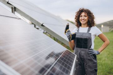 Female engineer working with drill installing solar panels in power station