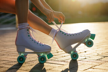 Woman lacing retro roller skates at sunset closeup outdoor summer lifestyle