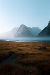 Serene mountain landscape with misty lake and golden grass at sunrise