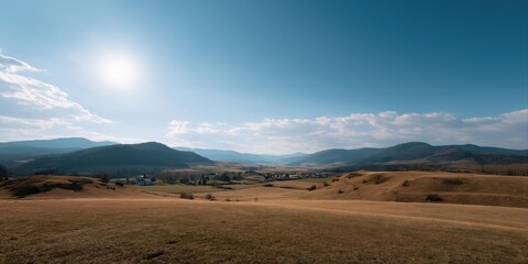 Fototapeta premium Expansive mountain valley under clear blue sky with sunlit landscape