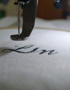 Close-up of a sewing machine embroidering the word "Lin