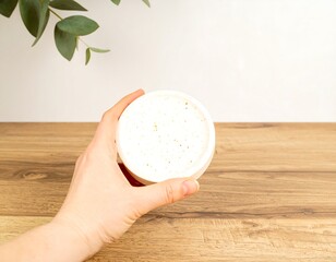 Hand holding a white round container with small holes