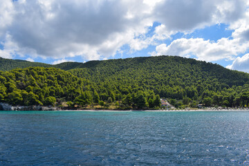 Beautiful Greek island landscape with lush, thick woodland and turquoise tropical waters. Mountains, dense green forests, white rocks and clear blue waters make up the idyllic travel destination.