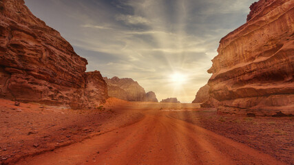 Sunset casts golden light over red rock formations in desert landscape. Wadi Rum, Jordan.