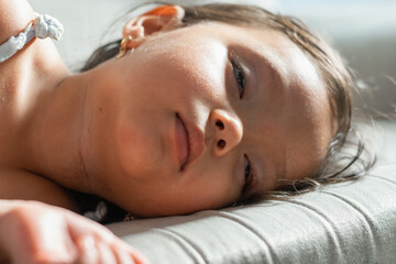 Close-up of a little girl's face resting on a sofa cushion, soft natural light and shallow focus, peaceful nap at home