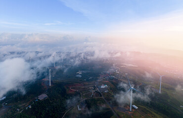 Obraz premium Wind generators turbines on summer landscape with green tea hills on sunset