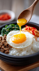 Delicious bibimbap with egg yolk breaking, capturing authentic korean cuisine