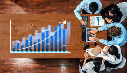 A diverse group of professionals engaged in strategic discussions about financial growth, analyzing charts, and utilizing technology in a modern office setting. Amity
