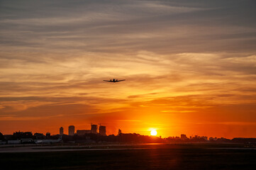 Airplane silhouette at sunset in Buenos Aires over Aeroparque Jorge Newbery airport runway....