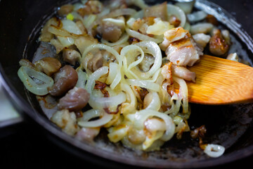 Pork and onion cut to little pieces being roast in the pan
