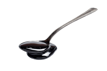 A metallic spoon holds a dark, viscous liquid.  The liquid spills slightly over the spoon's bowl