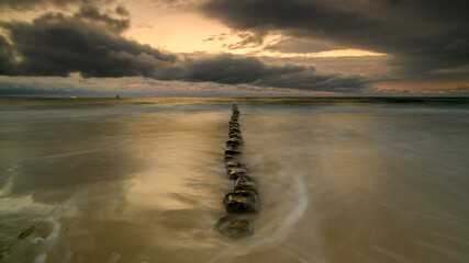 Stunning sunset over the Baltic Sea, capturing the warm golden hues reflecting on calm water. Serene coastal landscape with peaceful waves and a colorful sky.