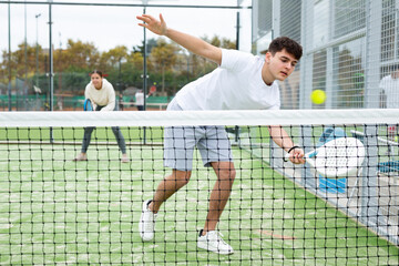 Portrait of emotional guy enjoying friendly padel tennis match at outdoors court