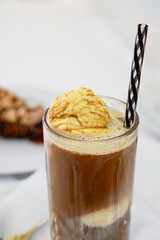 A tall glass of affogato coffee topped with a scoop of vanilla ice cream