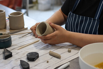 Female hands molding a clay cup in a pottery workshop