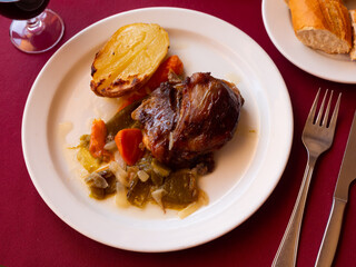Glazed sweet-sour Pork cheeks with baked potato and vegetable stew.