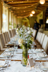 Elegant dining setup with floral centerpieces in a cozy, warmly lit restaurant during a festive gathering