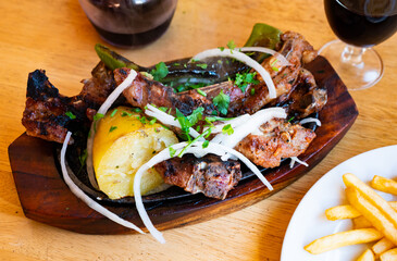 Grilled lamb ribs, potato and pepper grilled on firewood served with cut onion and greens