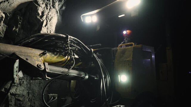 A driller works in a mine behind a drilling rig